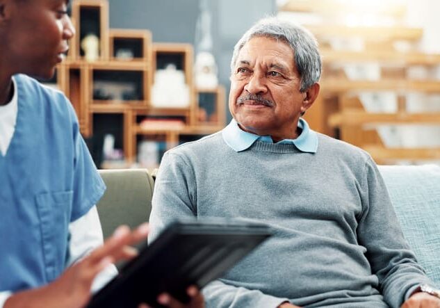 Old man, nurse and tablet in home for healthcare, medical support and test results. Retirement, senior patient and caregiver with technology in living room for help, checkup report and insurance app